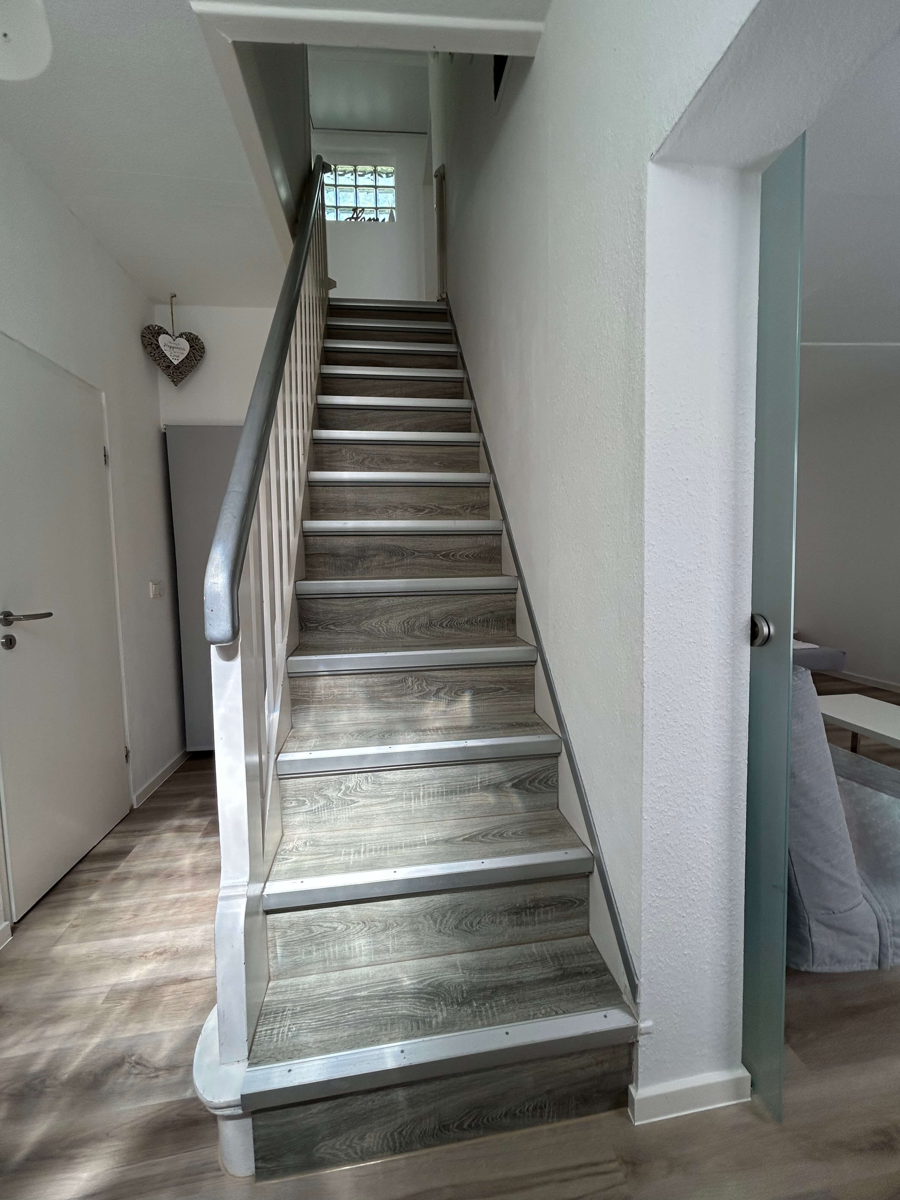 Quartier 26 – Helles Treppenhaus mit Holzstufen und weißem Geländer