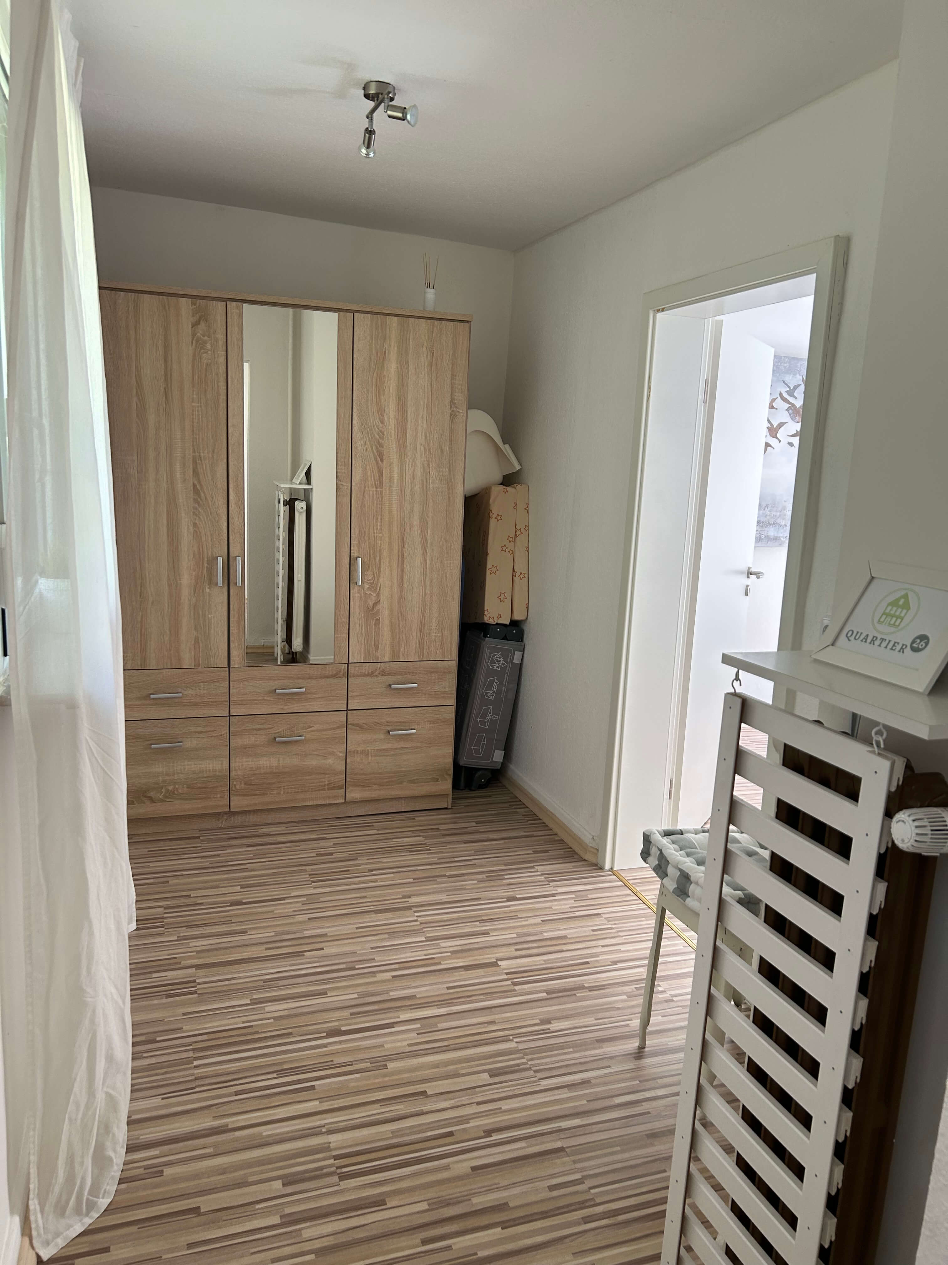 Quartier 26 – Schlafzimmer mit großem Holzkleiderschrank und Spiegel